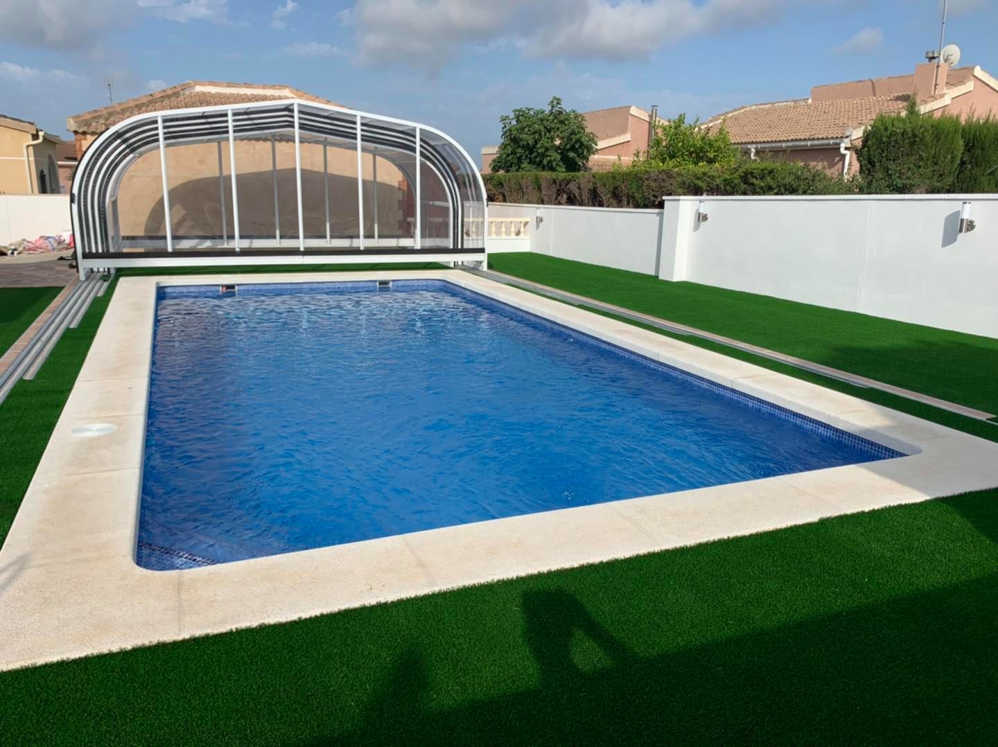 piscina con techo y césped artificial